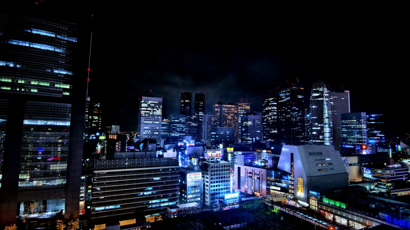 The Shinjuku skyline in Tokyo at night, office towers lit above the station district.